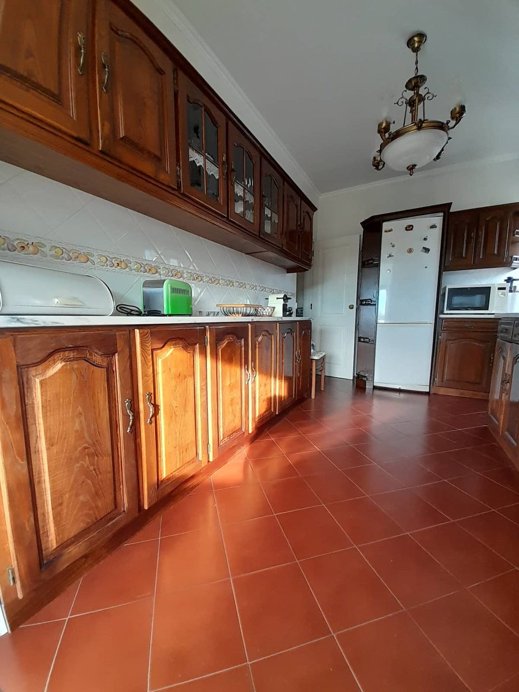 Cozinha em madeira com luz dourada a entrar pela janela