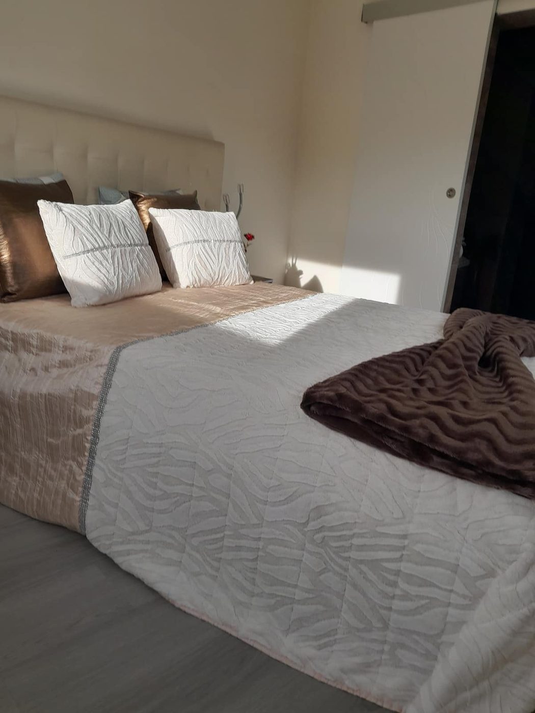 Pormenor da cama com almofadas em tons de creme e manta de lã